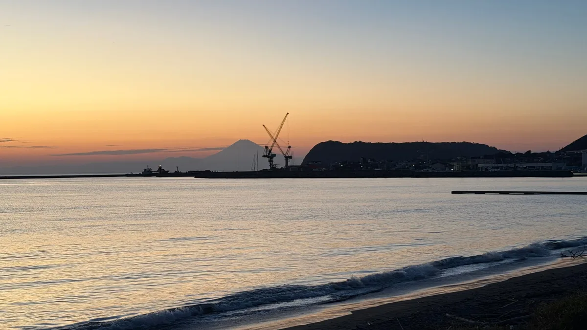 夕焼けの海の向こうに、富士山のシルエットが浮かぶ