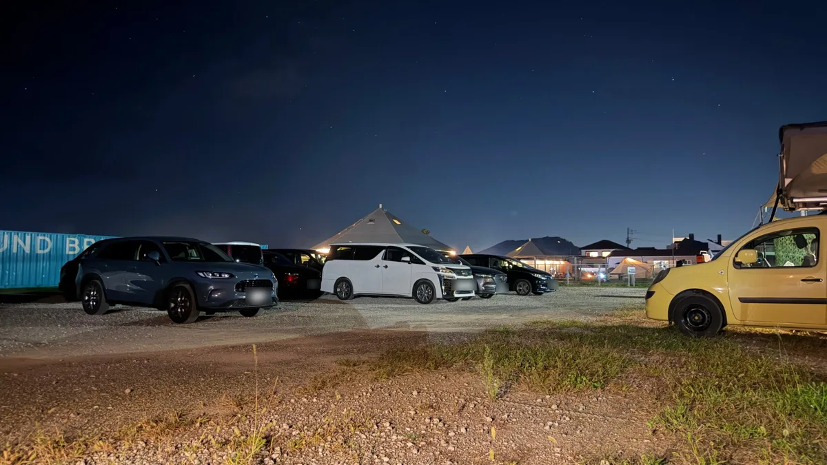 星空の下、キャンプ場の駐車スペースに並ぶ車