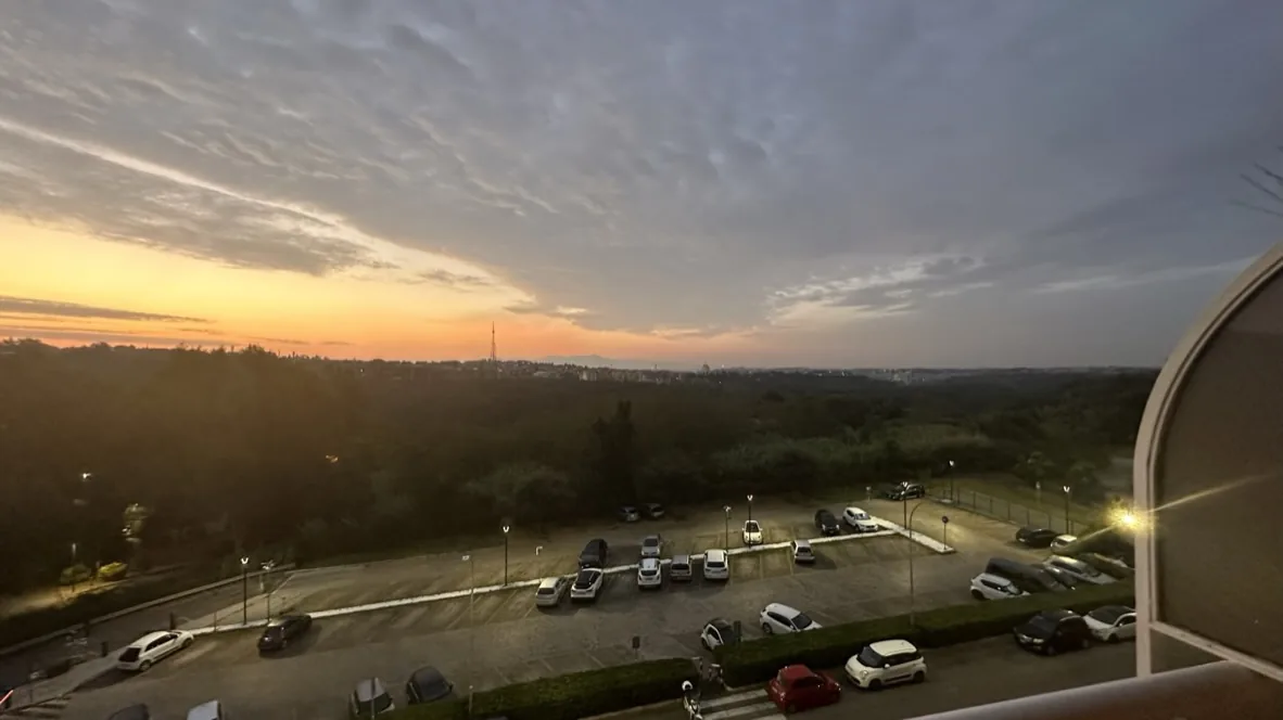 夕焼けの空と、ホテル前の駐車場と森