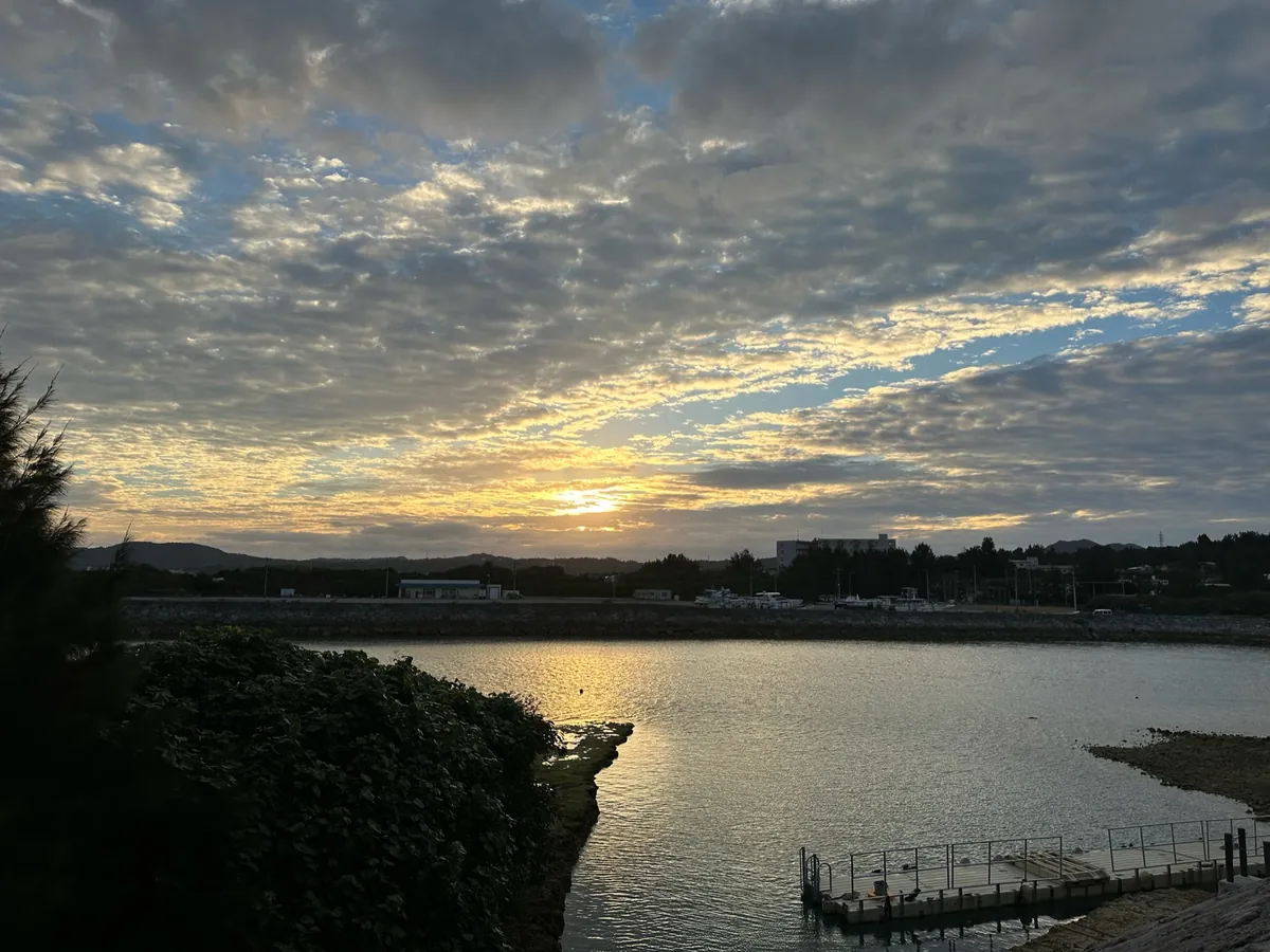 海辺から見た、雲の切れ間に沈む夕日
