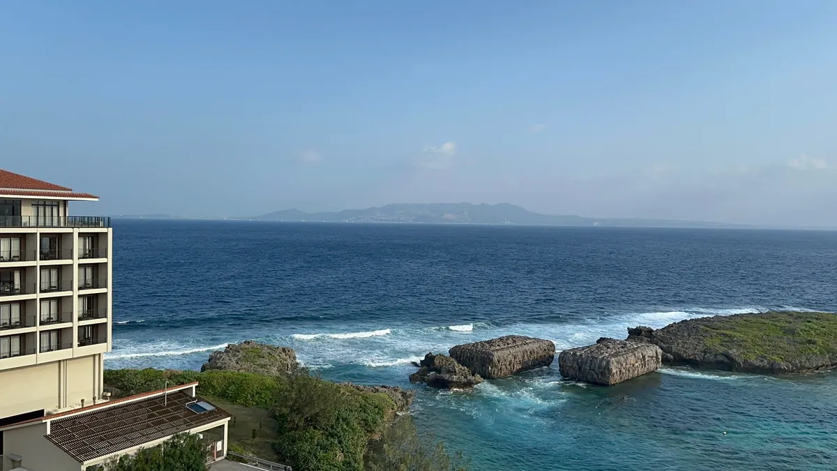 客室から見た、岩場に白い波が立つ青い海