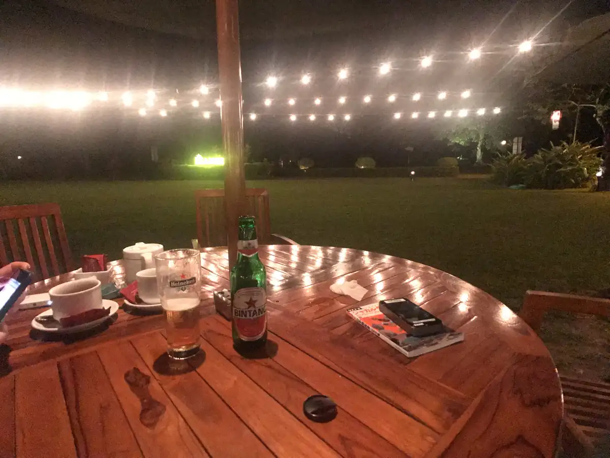 夜、電球の灯る芝生の前のテーブルにビール