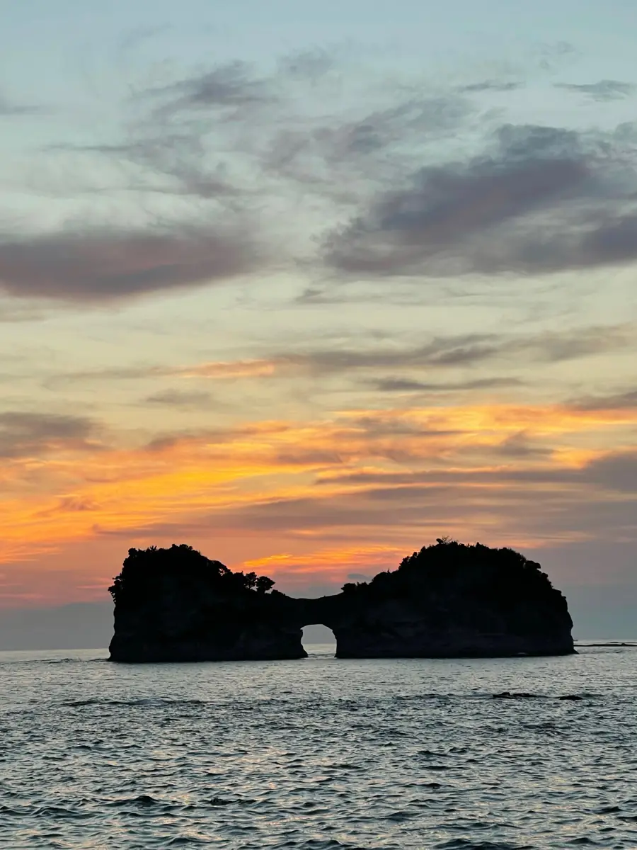 夕暮れの空を背に浮かぶ円月島のシルエット
